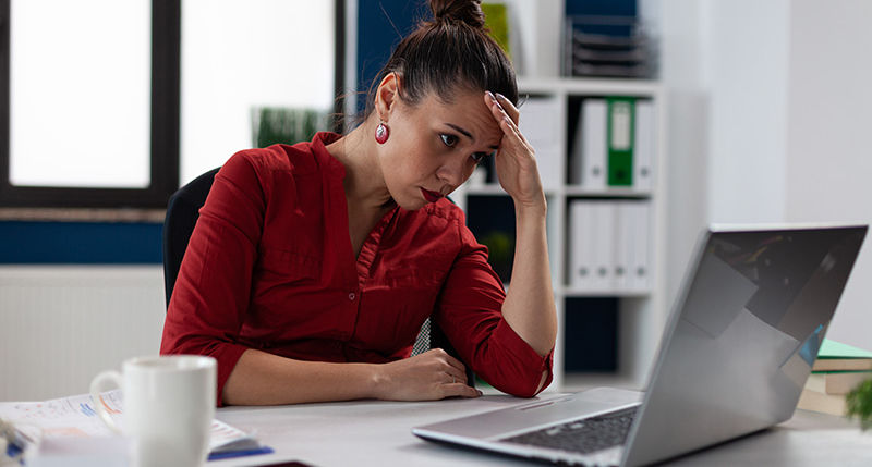 An overwhelmed business woman looking at her computer