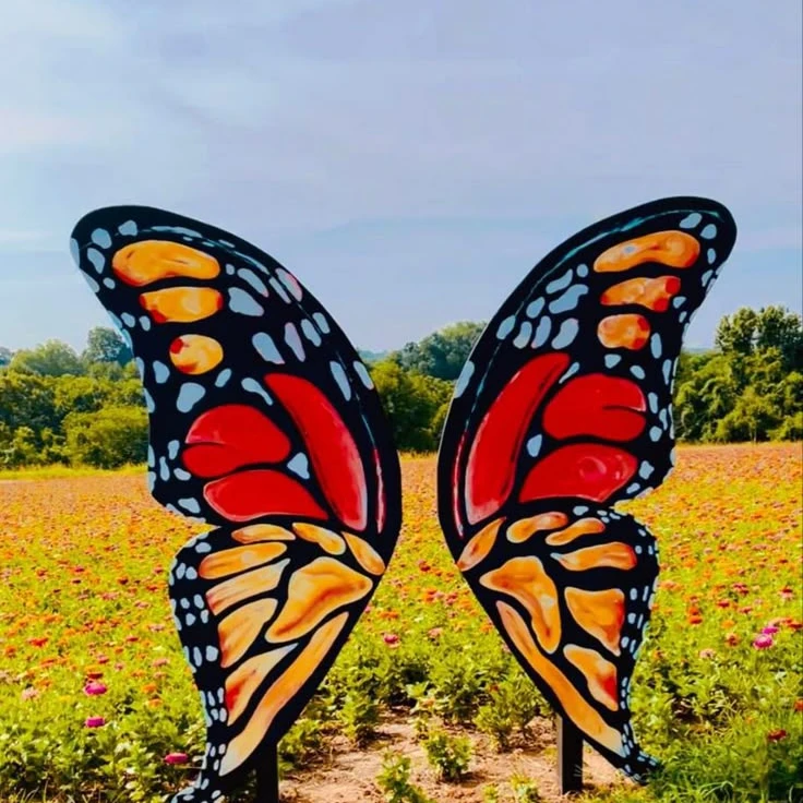 Large butterfly wings stand in a field of flowers for visitors to pose with