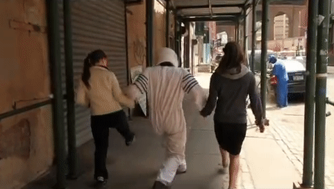 repeating video gif of two women and an astronaut taking big steps on a sidewalk in Brooklyn NY that was part of an interactive theater performance performance by the Institute for Psychogeographic Adventure.