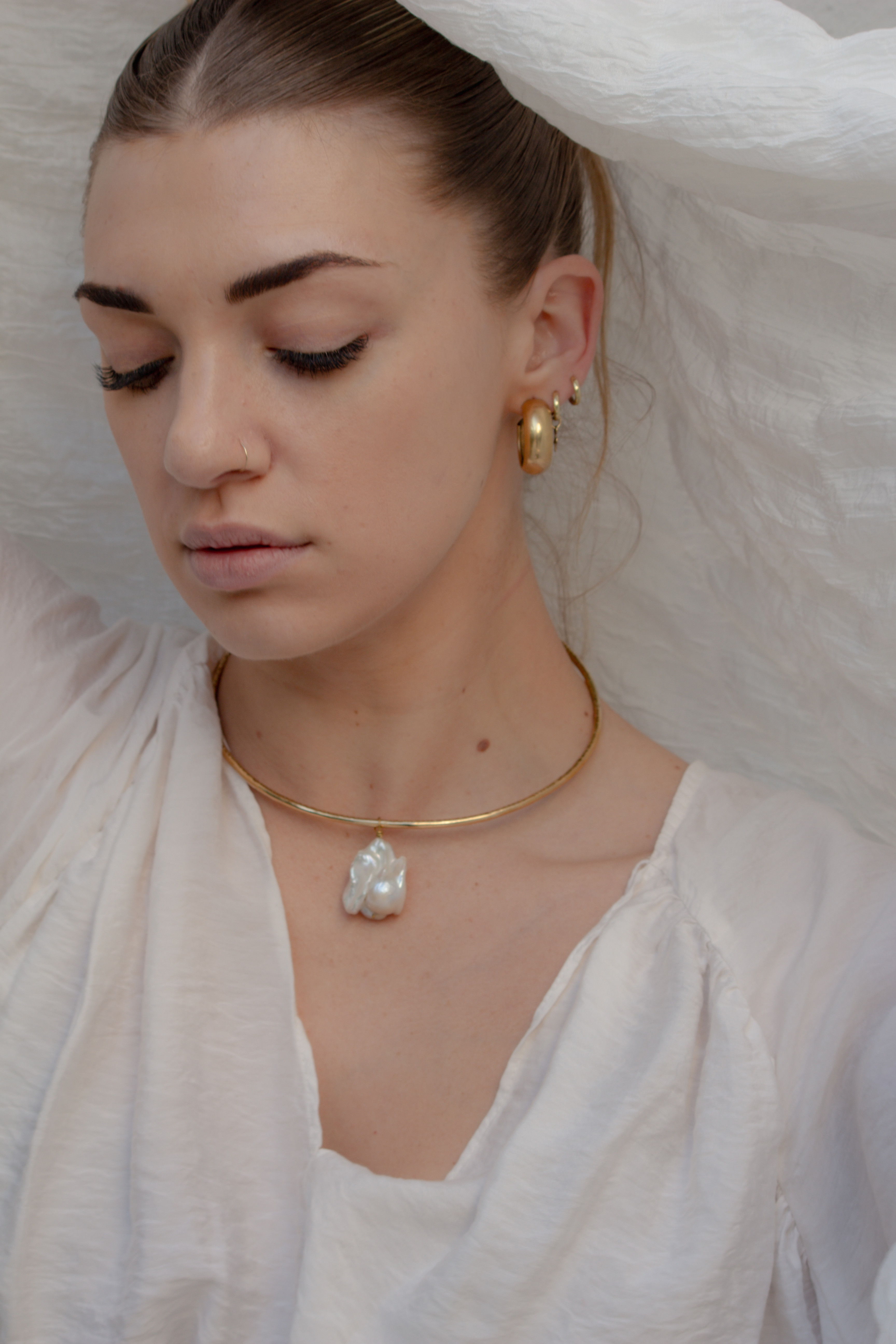Clio baroque pearl necklace featuring a freshwater baroque pearl suspended from a textured hand-formed brass