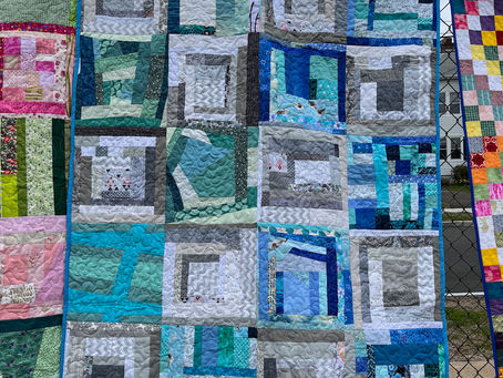 blue, green, gray improvisational quilt blocks hanging on a fence