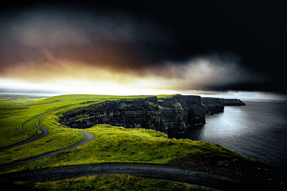 Green cliffs above the sea beneath storm clouds at the Cliffs of Moher, Ireland — Nick Calero