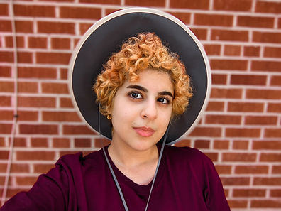Artist Sakalda Sara Al Dabbagh Tucson Artist standing in front of a red brick building