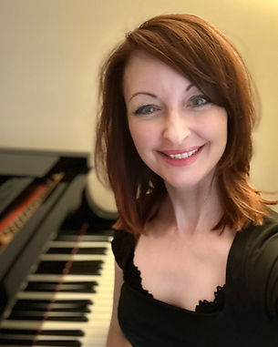 Kelly Winter smiling by her piano during a live music event