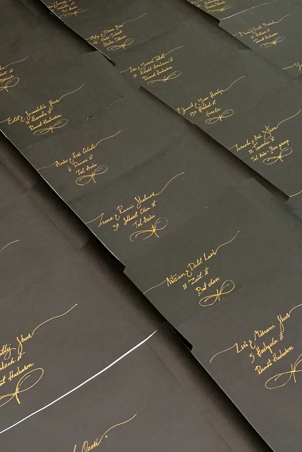 מעטפות מעוטרות בכתב קליגרפי בדיו זהב על גבי מעטפות שחורות
