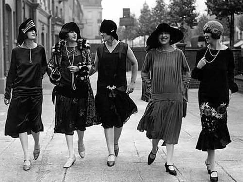Black and white photograph of five flappers walking down a street
