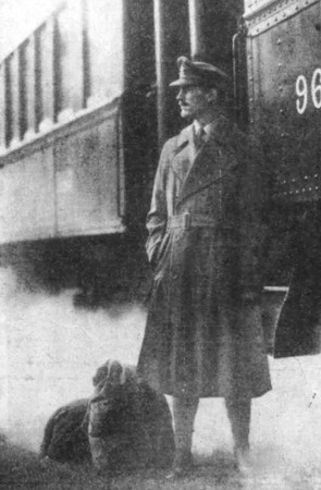 British Army officer in the First World War wearing a trench coat in front of a train.