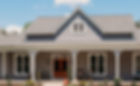 Front view of a modern home with gray siding, a pitched roof, and wooden double doors, featuring a spacious front porch with rocking chairs and decorative plants.