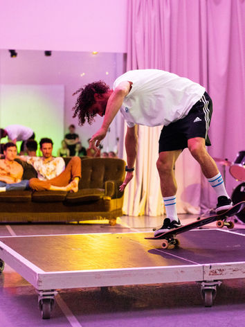 Matty keeps on skateboarding on the platform with weals. He is balancing in the two back weals of his skateboard, his torso moves down, front and sideways. Márcio and Sindri are at the sofa, betting if Matty will fall or not. © Photos: Dirk Rose / PACT Zollverein