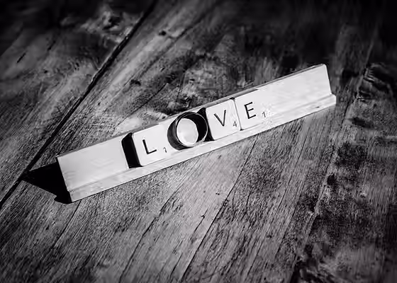 Photographe de mariage à Fontenay-Trésigny 77 - Détail d'une alliance remplaçant la lettre O du mot LOVE en lettres de Scrabble.