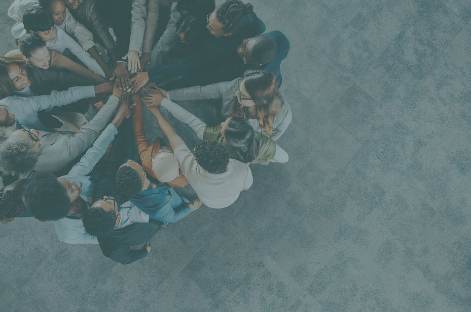 Group of people in a circle holding their hands together in the center