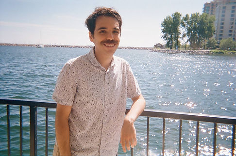 Image of the author standing in front of a scenic lakeside view.