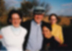 Three women and a man smiling, with arms around each other