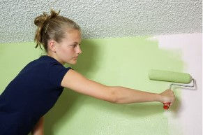 Teen girl on a ladder holding a paint roller and stretching to reach an unpainted part of the wall. Credit: Pastor Scott via Getty Images signture via Canva Pro.