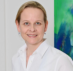 Porträt einer lächelnden Frau mit weißem Oberteil. Zu sehen ist Frau Anne Hesse
