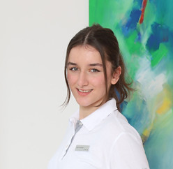 Porträt einer lächelnden Frau mit weißem Oberteil. Zu sehen ist Frau Esra Kamberi