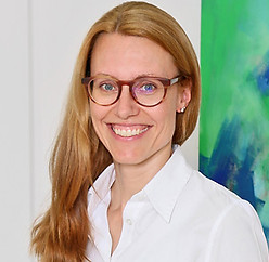 Lächelnde Frau mit Brille, weißes Hemd. Zu sehen ist Frau Nicole Jaenicke