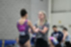 gymnastics coach spotting young athlete on balance beam, USA Gymnastics certified instructor helping child learn gymnastics s