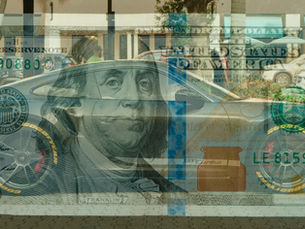 A photo of a hundred dollar bill superimposed over a photo of a Porsche sports car