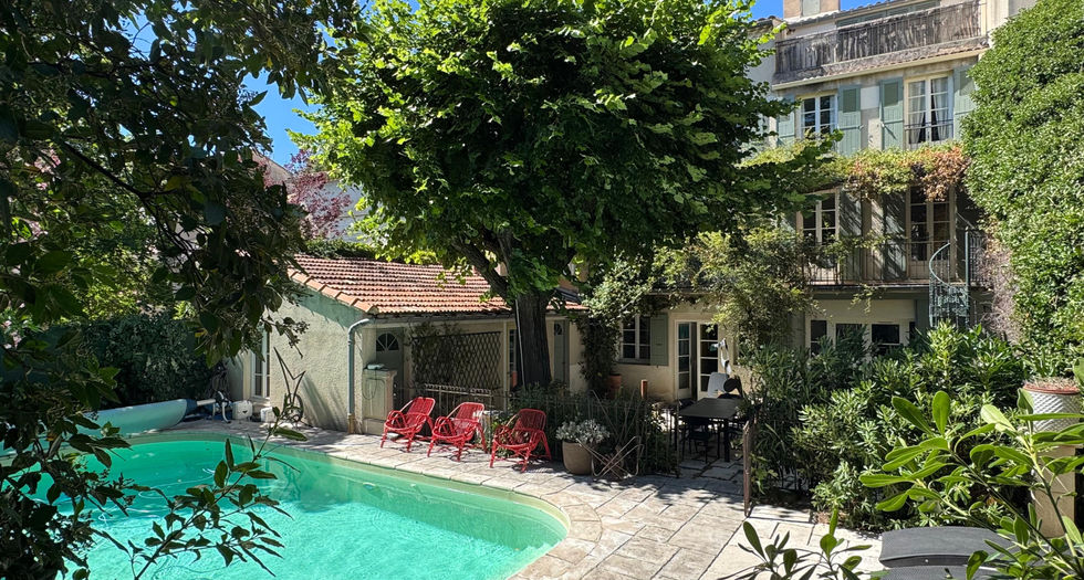 Piscine et terrasse ombragee avec chaises rouges devant facade maison en pierre carpentras