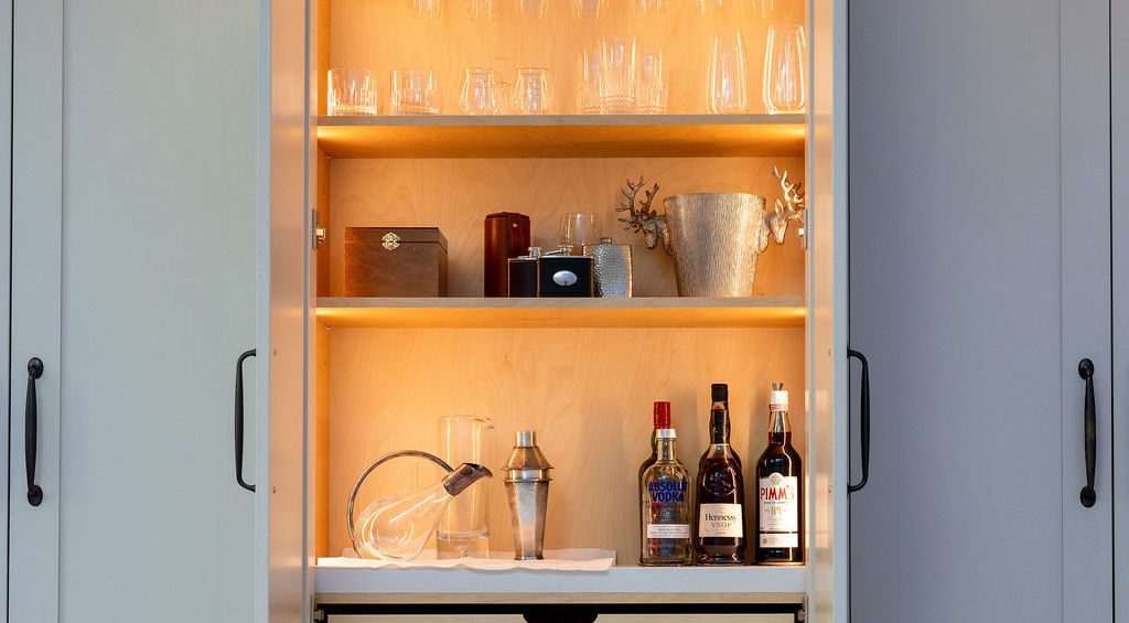Illuminated bar cabinet with glassware and bottles