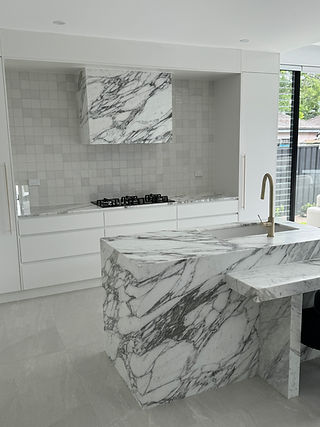 Beautifully appointed kitchen with stone island and rangehood feature and finished with brushed gold hardware.