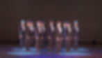 Dancing troupe in fedora hats and suits.