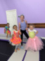 Four smiling girls in colorful dresses and a tiara.