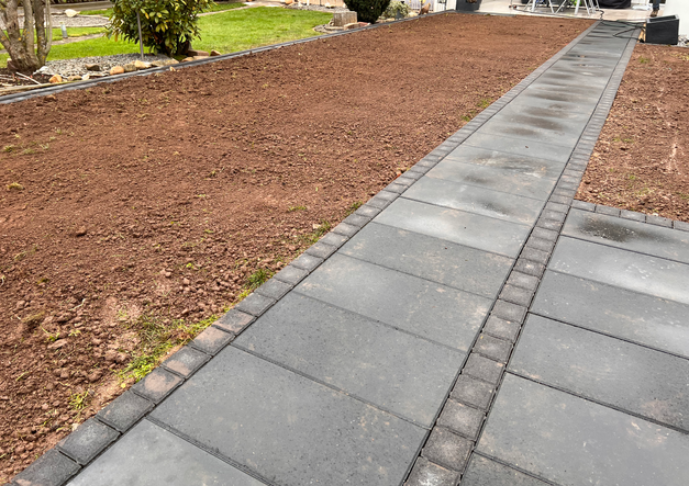 Dunkle Pflastersteine Weg führt durch Garten, Platten legen, vorbereiteter Boden.