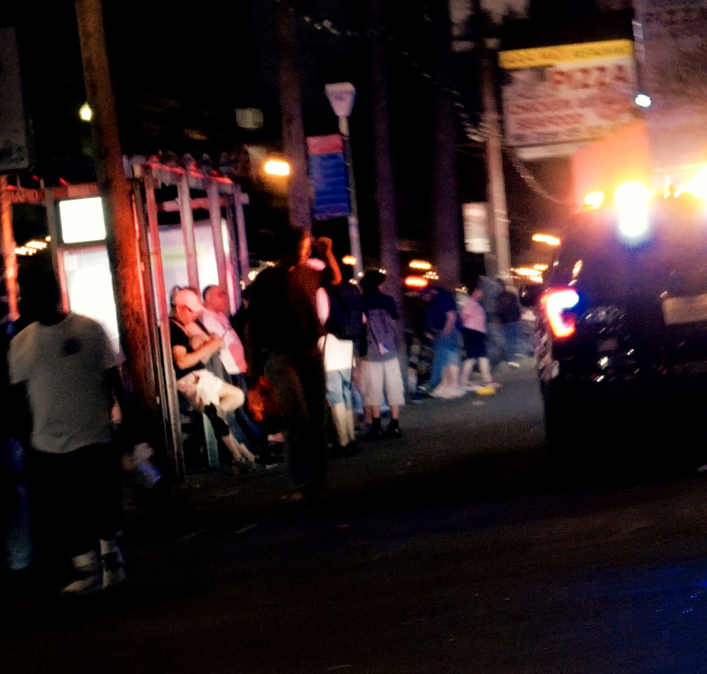 Night scene of people gathered on a Bay Area street with emergency lights