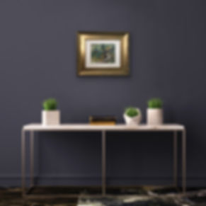 gold framed landscape on dark wall above tabl