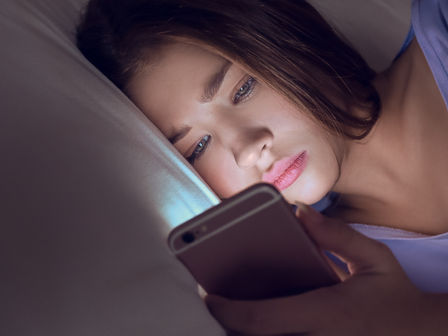 Chica joven mirando el móvil tumbada en la cama