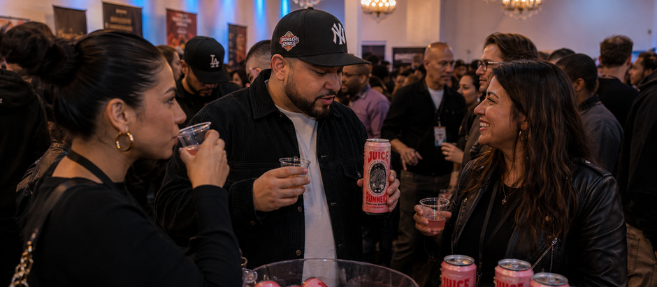 Guests tasting Juice Runners Paloma REMIX mezcal cocktails during Island Spirit Cocktail Convention at The Experience on Long Island with crowded hospitality networking and RTD activation booths.