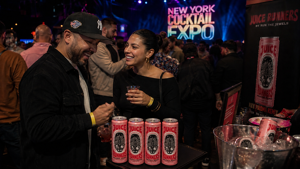 Guests tasting Juice Runners Paloma REMIX canned cocktails at New York Cocktail Expo inside Melrose Ballroom with nightlife lighting and hospitality crowd in Queens, New York City.
