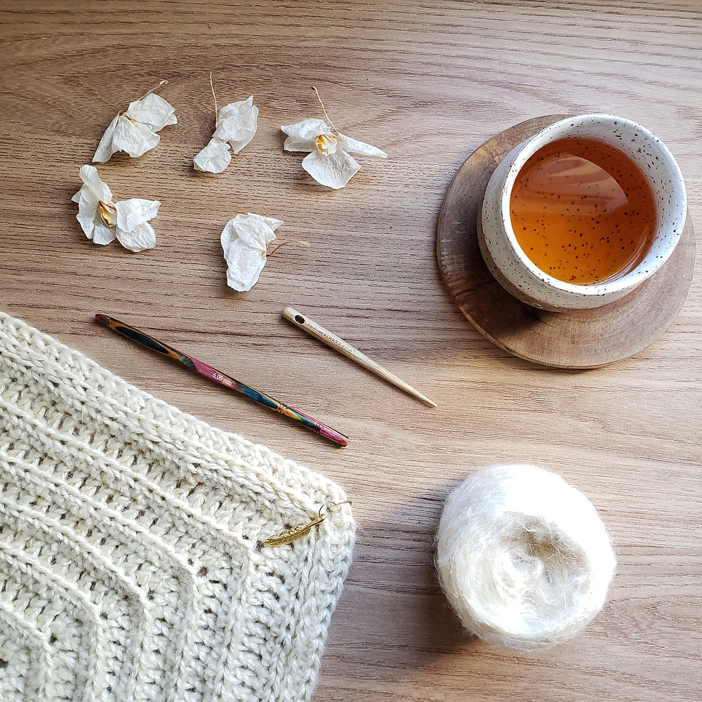 Xale de crochê pluma com novelo de lã mohair, agulha de crochê colorida, agulha de tapeçaria, copo de chá oriental e flores secas de orquídea,