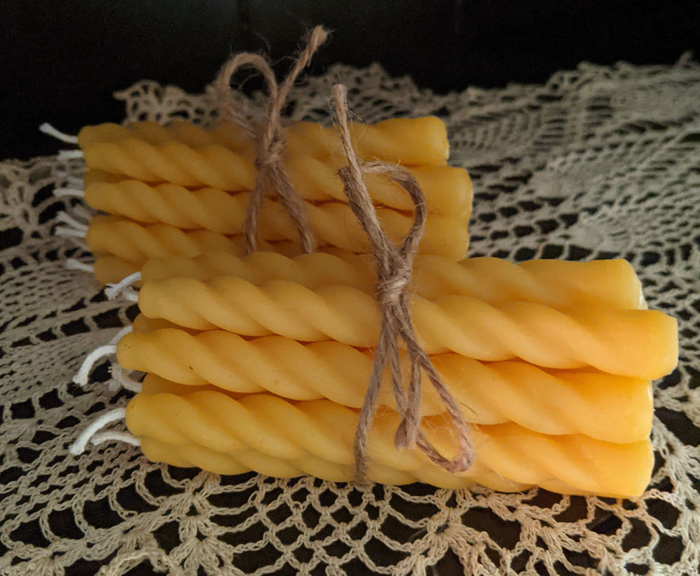 Two bundles of twisted yellow candles tied with twine on a lace doily.