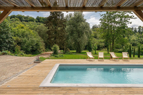 Vue sur une piscine moderne et un jardin verdoyant à proximité d'une terrasse en bois, mise en valeur par Julien Loize, photographe architecture et design.