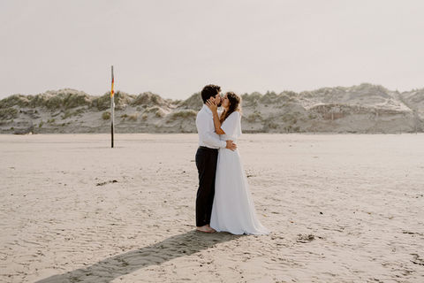 Photo romantique d’un mariage en Baie de Somme capturée par Julien Loize, photographe de mariage en Picardie : les mariés s’embrassent sur une plage paisible, entourés d’un décor naturel et lumineux.