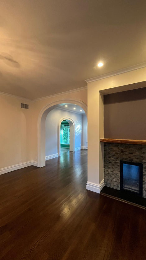 Room with archway and fireplace, wooden floor.