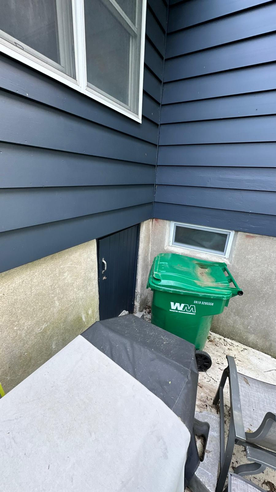 Small outdoor area with a green waste bin.
