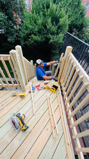 Person constructing wooden deck railing outdoors.