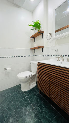 Small modern bathroom with wooden accents and green tiles.