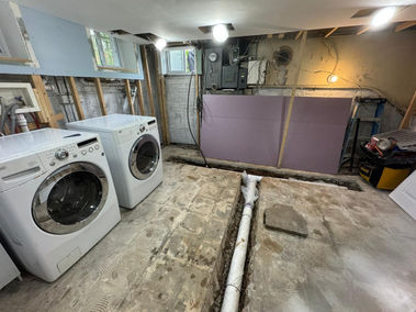 Basement renovation with laundry machines and exposed walls.