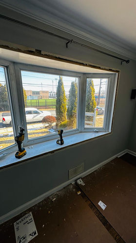 Room with bay window and two decorative statues.
