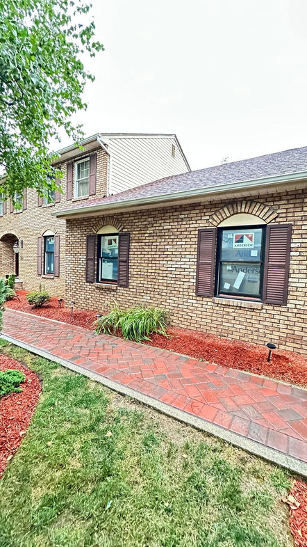 Brick house with arched windows and landscaped walkway.