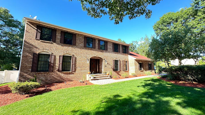 Brick house with green lawn and clear blue sky.