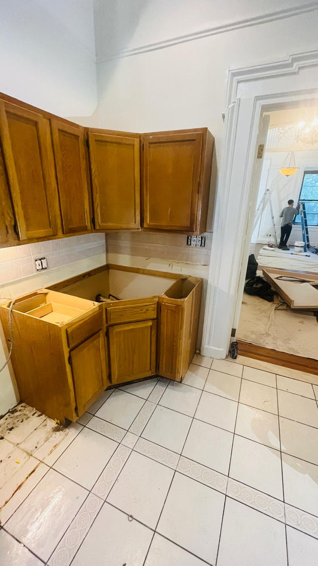 Wooden kitchen cabinets in a partially renovated room.