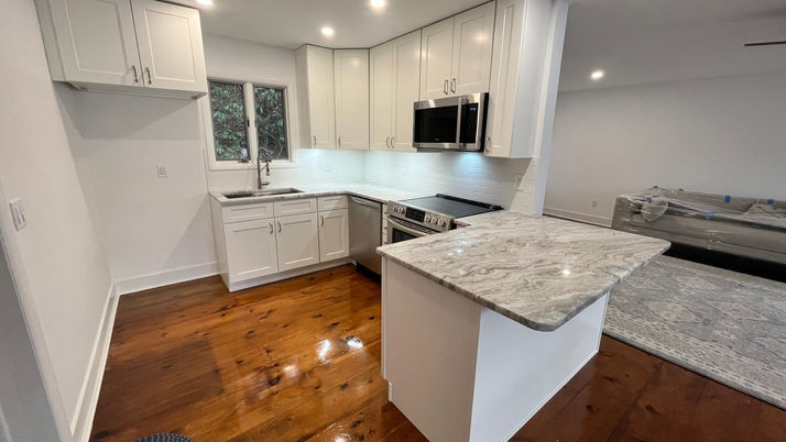 Modern kitchen with white cabinets and marble countertop.