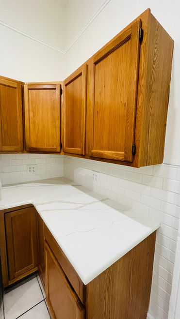 Wooden kitchen cabinets with white marble countertop.