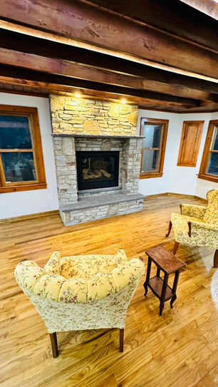 Cozy room with stone fireplace and yellow chairs.